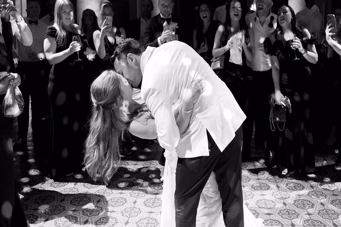 Primo piano in bianco e nero dello sposo in smoking che stringe la sposa in un romantico casqué sulla pista da ballo di Villa Erba, durante i festeggiamenti serali con gli invitati.