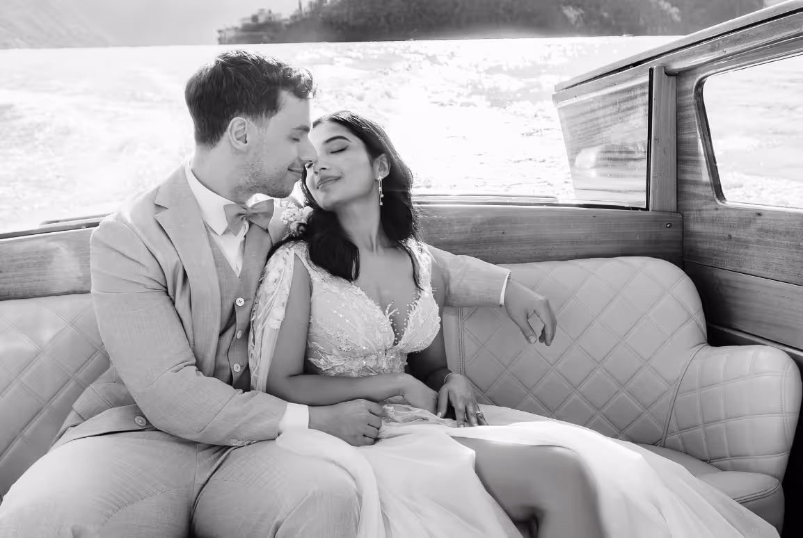 A romantic black and white photograph of Puja and Rino cuddling on the leather seats inside a traditional wooden speedboat on Lake Como.